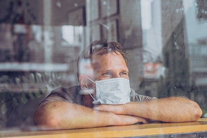 Man wearing a mask looking through window